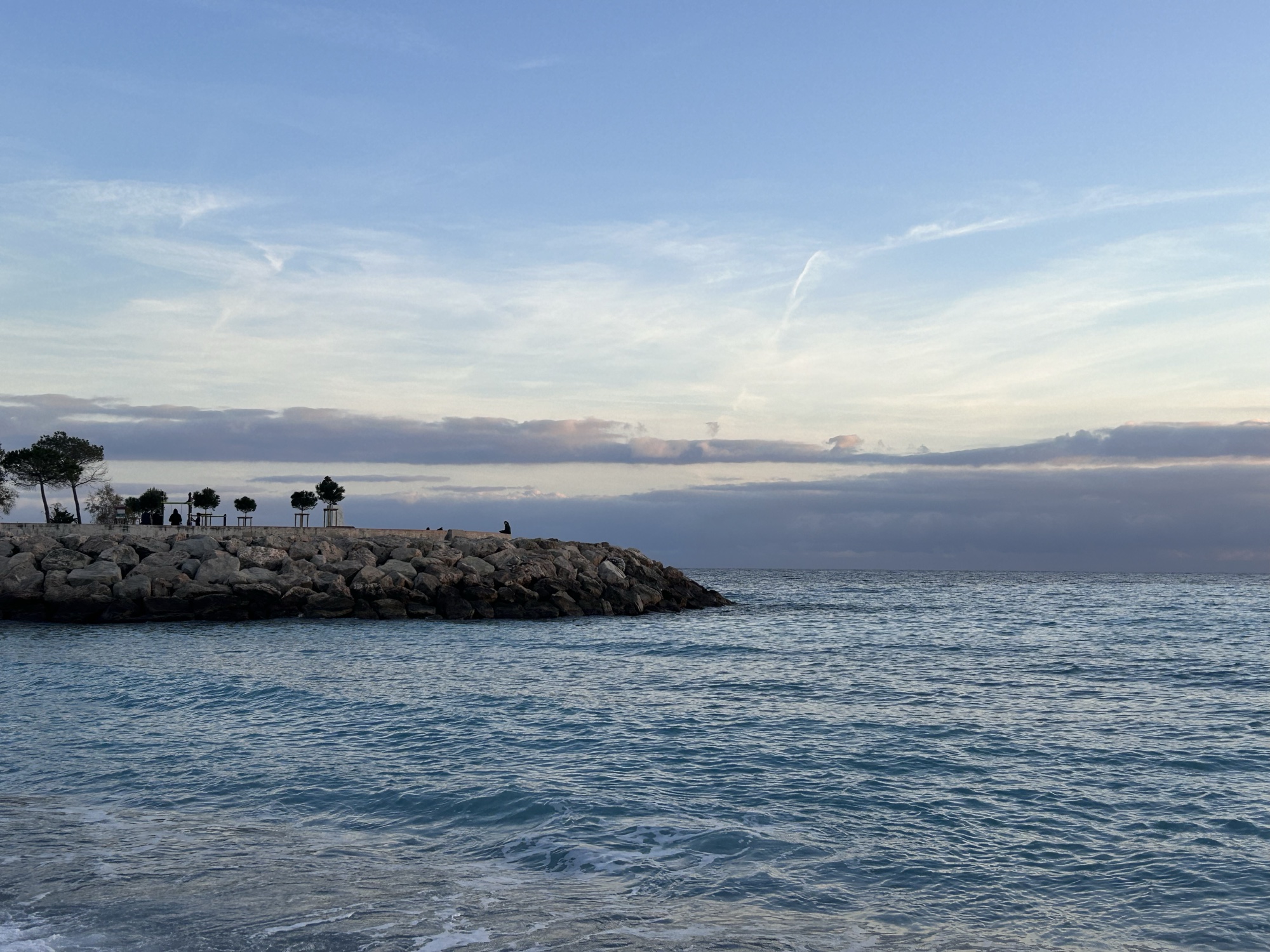 A rocky breakwater beside the sea at dusk